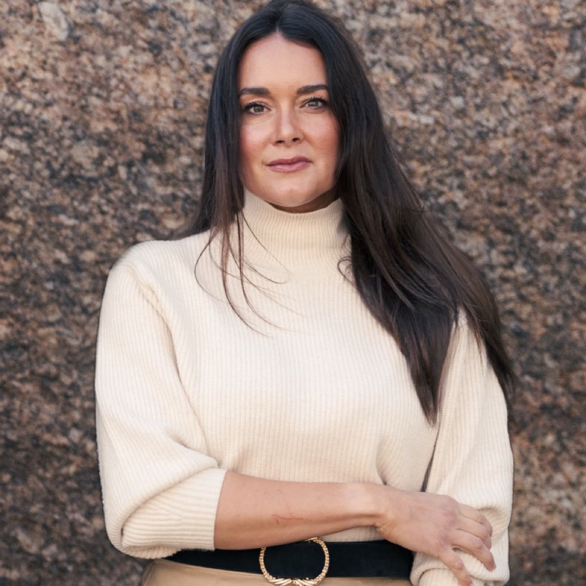 Portrait of Annette Thurmon in a cream sweater against desert rock