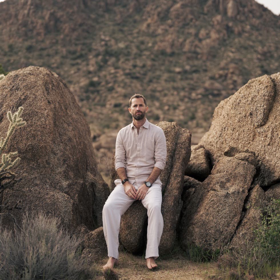 Jared Thurmon seated on desert boulders in the late-day sun